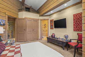 Bedroom with wood walls, light carpet, high vaulted ceiling, connected bathroom, and recessed lighting