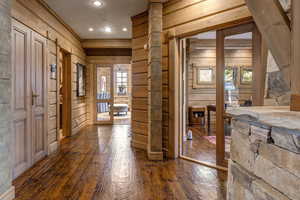 Hallway featuring wood walls, dark wood finished floors, plenty of natural light, and recessed lighting