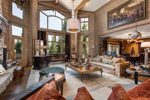 Living room featuring wooden walls, a chandelier, beamed ceiling, high vaulted ceiling, and wood finished floors