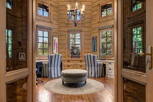 Sitting room featuring healthy amount of natural light, hardwood / wood-style flooring, built in desk, and a high ceiling