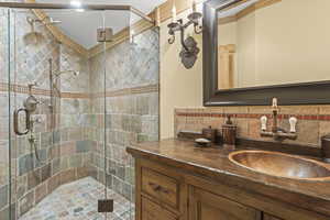 Bathroom featuring vanity, a shower stall, and backsplash
