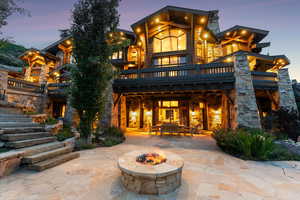 Back of house featuring stone siding, an outdoor fire pit, a balcony, a patio, and stairway