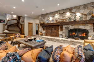 Living room featuring a stone fireplace, recessed lighting, stairway, and carpet