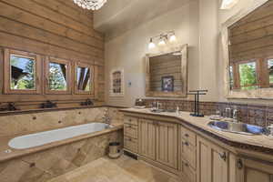 Bathroom with a garden tub and light stone finish flooring