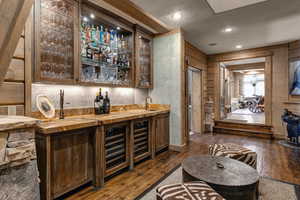 Indoor wet bar featuring wooden counters, dark wood-style flooring, glass insert cabinets, recessed lighting, and dark brown cabinetry