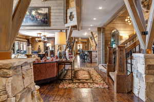 Living area with wood walls, stairway, a chandelier, dark wood-style floors, and recessed lighting