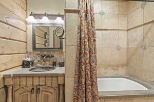 Bathroom with vanity, decorative backsplash, tile walls, and tiled shower / bath combo