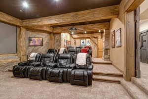 Cinema room with a barn door, carpet, and beam ceiling
