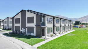 View of side of property with stucco siding, a residential view, a lawn, and a mountain view