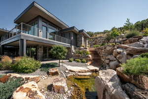 View of yard with a patio area, stairs, a balcony, and a small pond