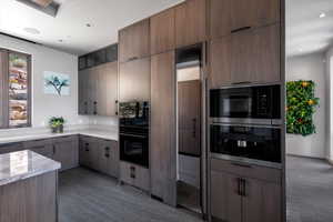 Kitchen featuring light stone counters, stainless steel microwave, recessed lighting, and modern cabinets