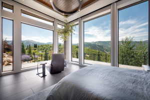 Bedroom with a mountain view, access to exterior, a view of trees, and wooden ceiling