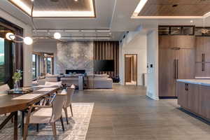 Dining area with a fireplace, wood ceiling, track lighting, and a raised ceiling