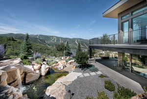 View of yard featuring a patio, a mountain view, a small pond, and a balcony