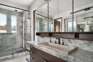 Full bath with a marble finish shower, vanity, and tile patterned flooring