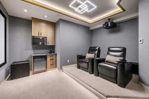 Cinema with light colored carpet, beverage cooler, a tray ceiling, and recessed lighting