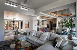 Living room with healthy amount of natural light, a chandelier, and a raised ceiling