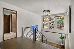 Stairway with a chandelier, wood finished floors, and recessed lighting