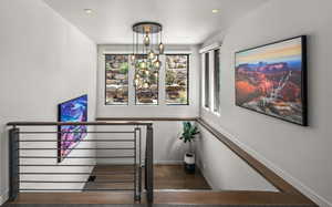 Stairs featuring wood finished floors and a chandelier