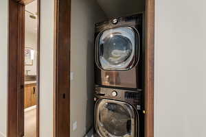 Washroom with stacked washer and clothes dryer and baseboards