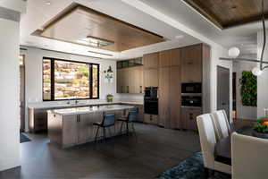 Kitchen with a tray ceiling, a kitchen island, a breakfast bar area, wooden ceiling, and black appliances