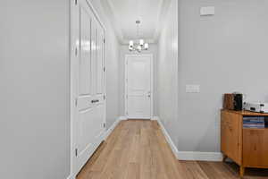 Corridor featuring light wood-style flooring and a chandelier