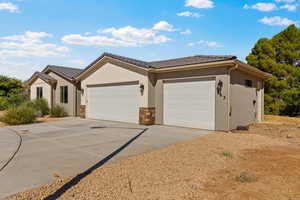 Ranch-style home featuring a tile roof, an attached garage, driveway, and stone siding