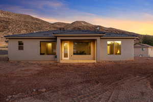 Back of house at dusk featuring stucco siding, a patio area, a tile roof, and a mountain view