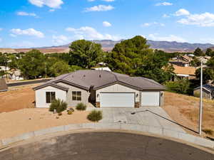 View of front of home with an attached garage, concrete driveway, a tile roof, board and batten siding, and stone siding