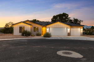Single story home with board and batten siding, an attached garage, driveway, a tiled roof, and stone siding