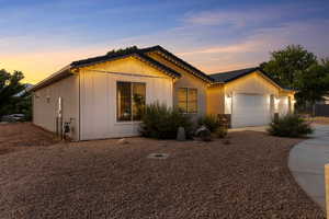 View of front of house with an attached garage, concrete driveway, a tile roof, and stone siding
