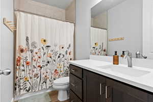 Full bathroom with vanity, dark wood-style floors, and curtained shower