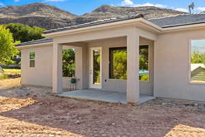 View of exterior entry with a mountain view, a patio area, and stucco siding