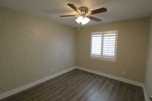 Spare room featuring dark wood-style floors and ceiling fan