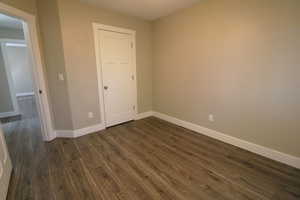 Unfurnished bedroom featuring baseboards and dark wood-style flooring