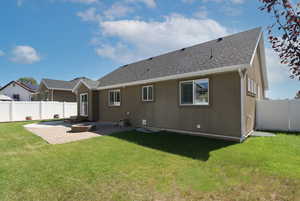 Rear view of property with a patio, a shingled roof, a fenced backyard, and a fire pit