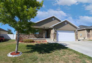 View of front of home with a garage, driveway, stucco siding, and stone siding