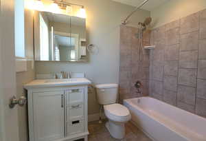 Bathroom with bathtub / shower combination, vanity, and light tile patterned floors
