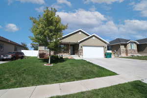 View of front of property featuring concrete driveway, stone siding, an attached garage, and stucco siding