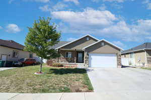 View of front of home with concrete driveway, an attached garage, and stucco siding