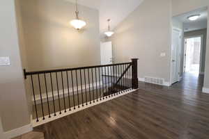 Staircase with wood finished floors and high vaulted ceiling
