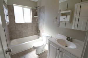 Bathroom with bathtub / shower combination, vanity, and light tile patterned flooring