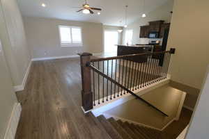 Stairs featuring plenty of natural light, wood finished floors, lofted ceiling, recessed lighting, and ceiling fan
