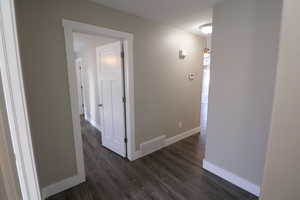 Hall with baseboards and dark wood-style flooring