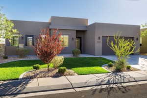 View of front of home featuring a garage, driveway, a front yard, and stucco siding