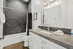 Bathroom with shower / bath combo with shower curtain, vanity, and decorative backsplash