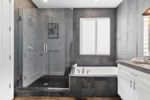 Bathroom featuring vanity, a bath, a shower stall, tile walls, and recessed lighting