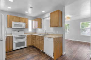 Kitchen with white appliances, a textured ceiling, dark wood-style flooring, light countertops, and recessed lighting