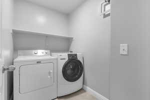 Washroom with washing machine and clothes dryer and baseboards