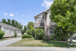 View of property exterior featuring a yard, brick siding, and stucco siding